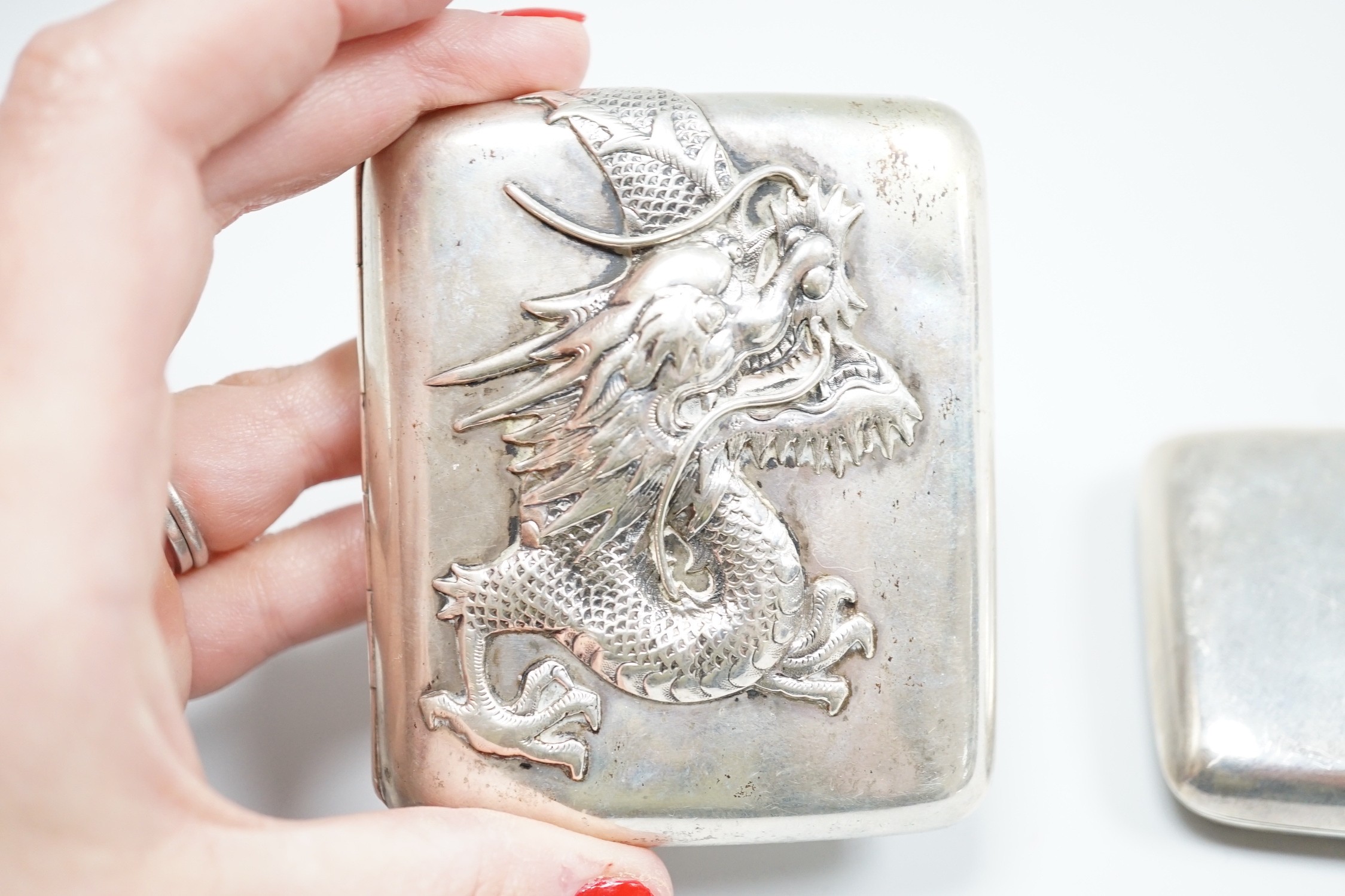 A white metal cigarette case, with applied dragon, 82mm, one other silver cigarette case and a Russian 84 zolotnik snuff box(tired).